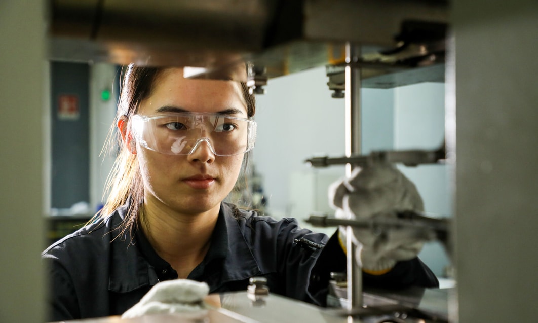 a person wearing safety goggles and gloves working in a factory