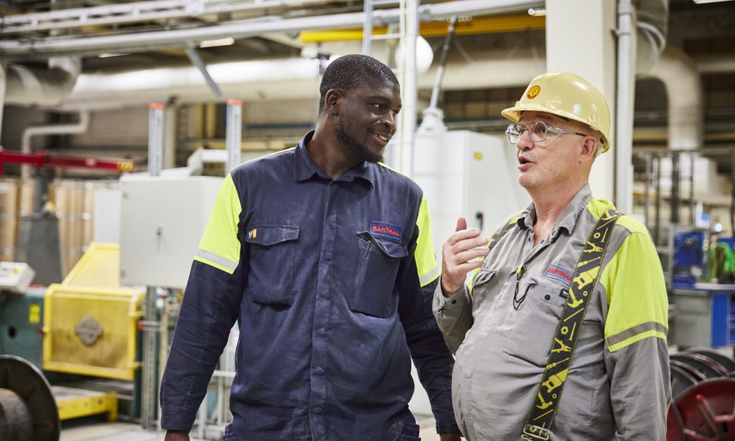 a person in a hard hat talking to a person in a factory