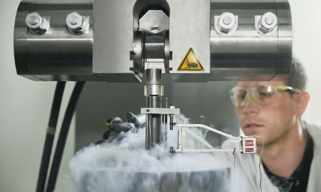 a person in a white coat and goggles working in a factory