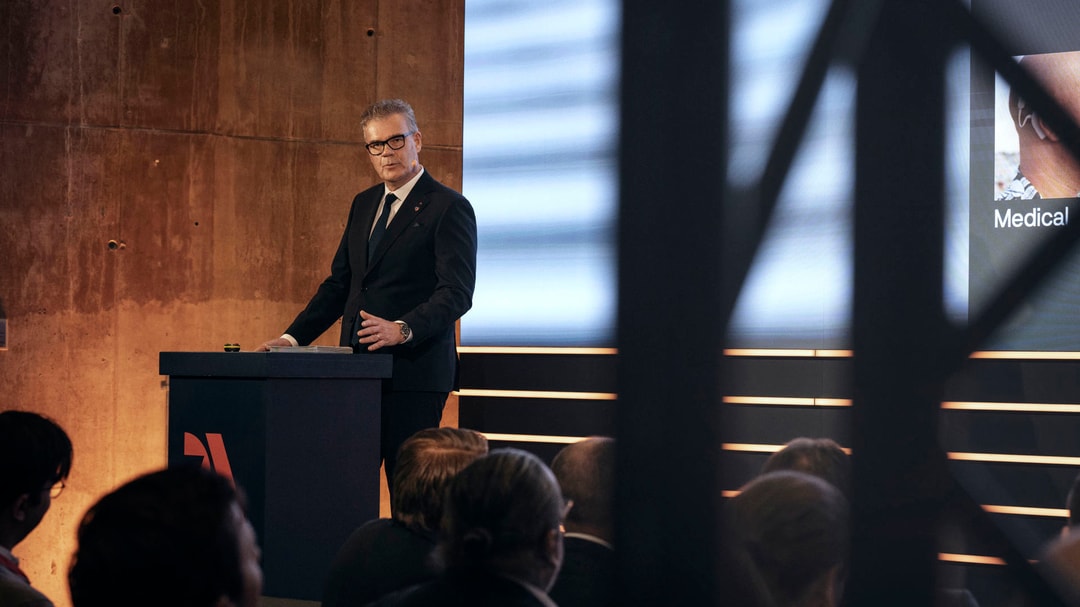 a person standing at a podium with a crowd watching