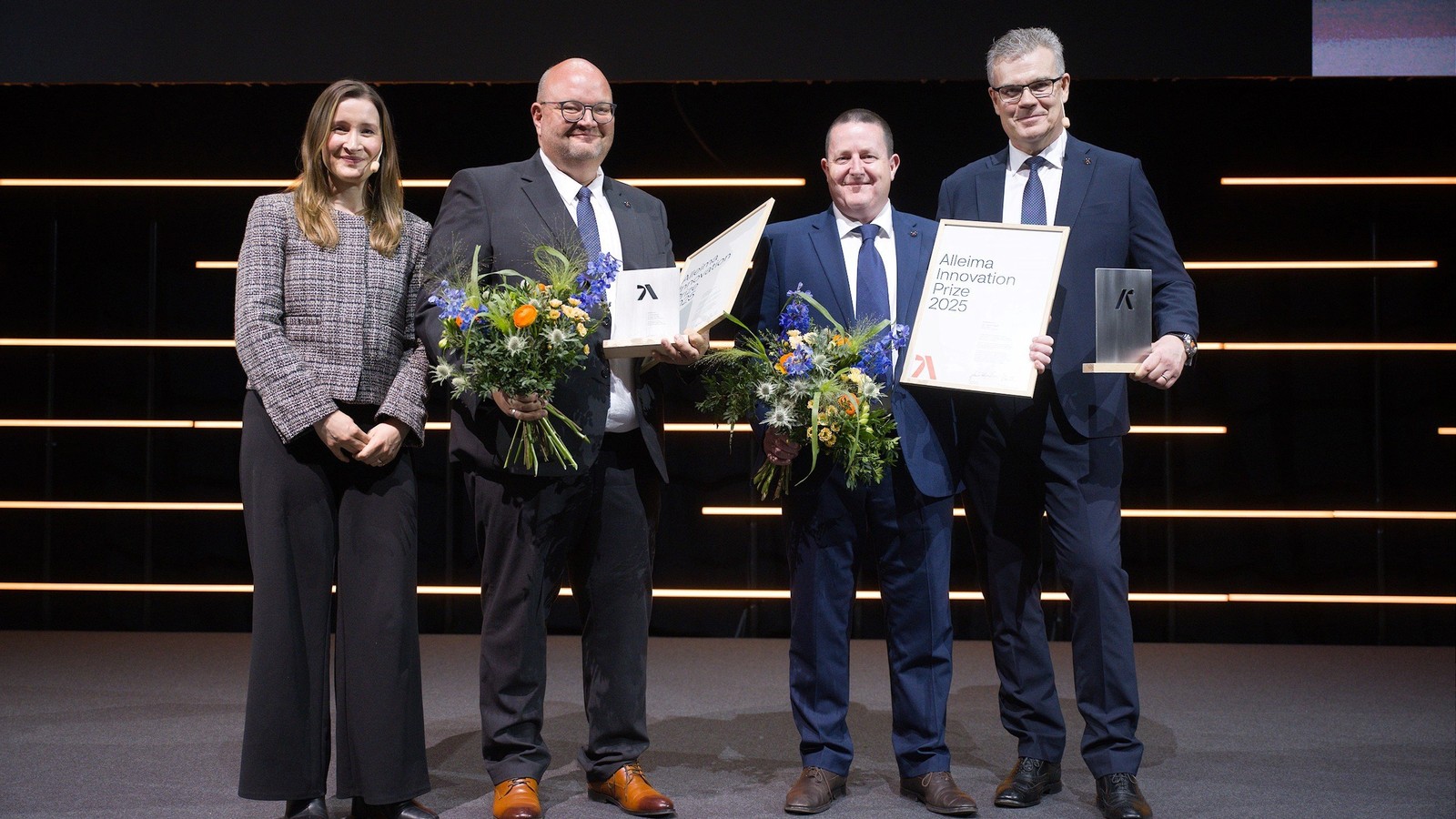 a group of people holding flowers and awards