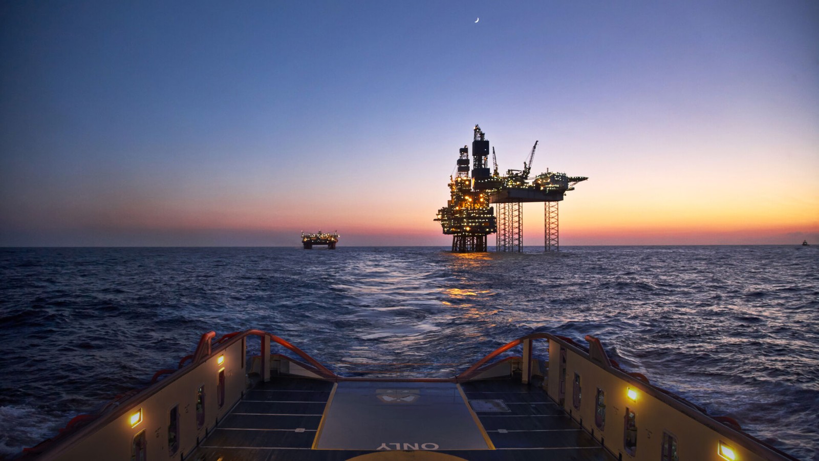 a boat in the water with a large oil rig in the distance