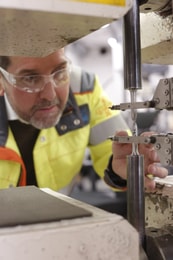 a person in safety glasses and goggles working on a machine
