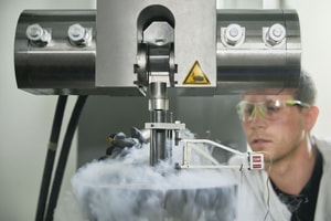 a person in a white coat and goggles working on a machine