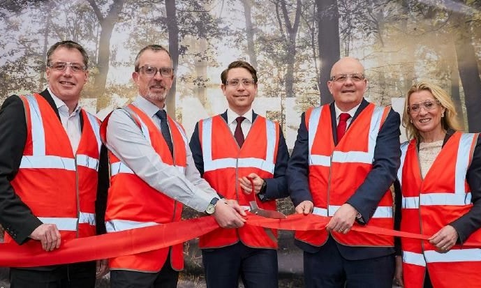a group of men in orange vests cutting a red ribbon