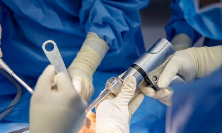a close-up of hands in gloves holding a surgical instrument